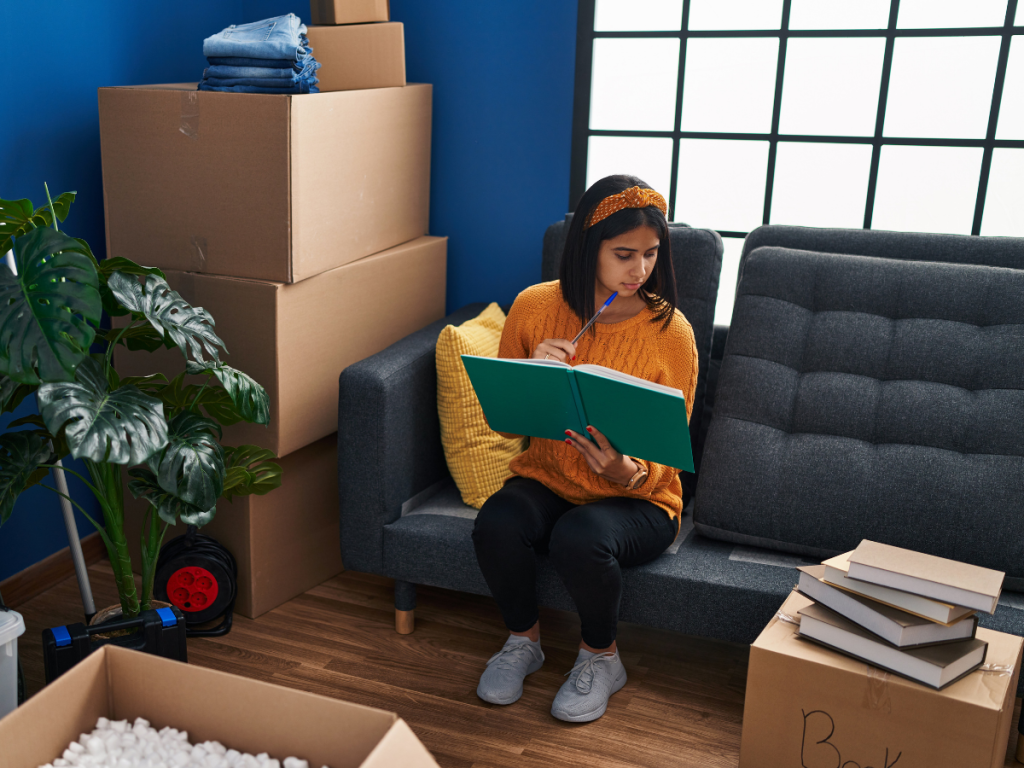 woman sitting on a couch and thinking surrounded by moving boxes